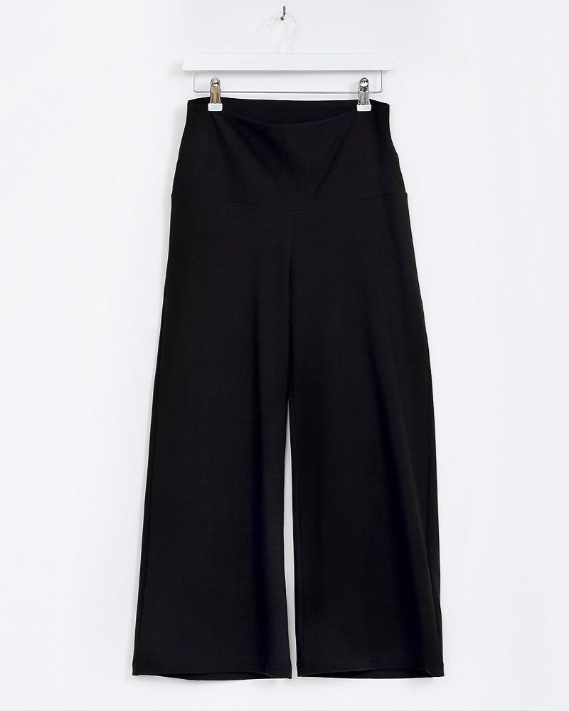 Black wide-leg pants hanging on a white background