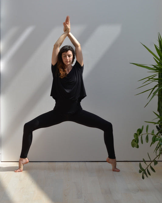 A person demonstrating a yoga pose wearing black leggings.